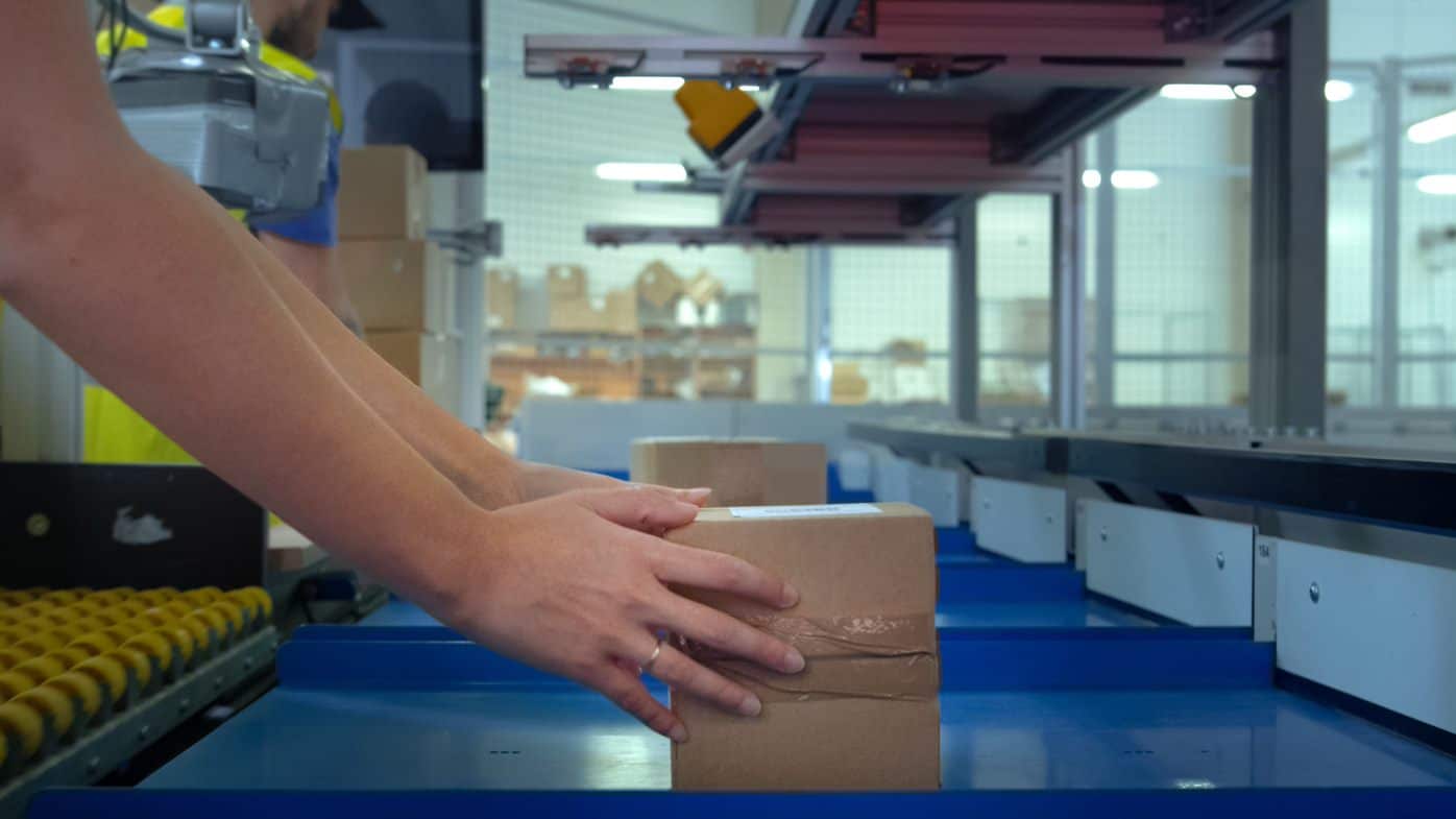 human holding a cardboard box from conveyor belt
